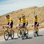 Four people on a bike with a blue sky in the background.