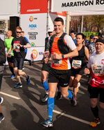 Man running at the Rotterdam Marathon with bright blue compression socks. 