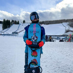 Loranne Smans standing while holding a snowboard and laughing.