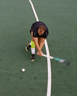 Man playing field hockey in full action seen from above.