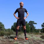 Erben Wennemars wearing orange shoes while posing in front of trees.