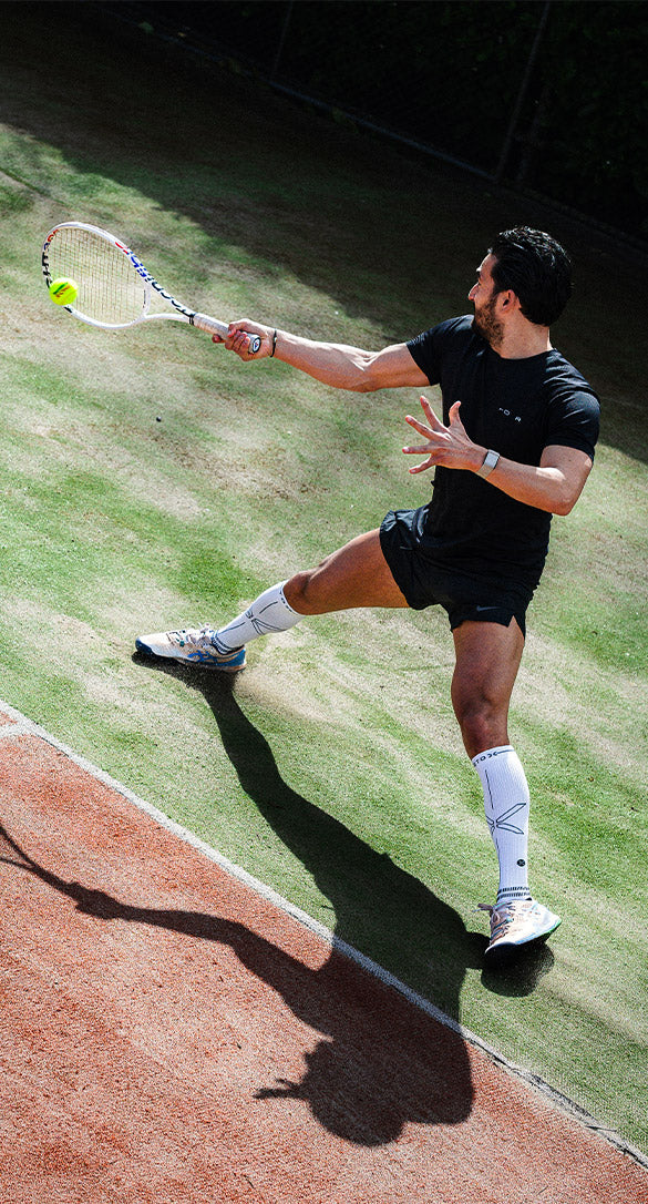 Man playing tennis in action with high knee socks